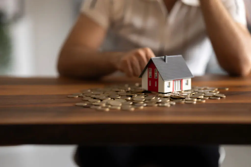Small model house resting on a pile of coins