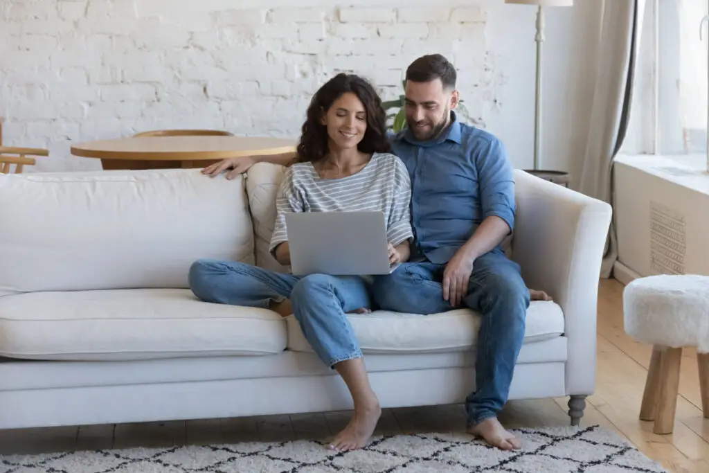 Couple comparing down payment assistance programs on a laptop at home