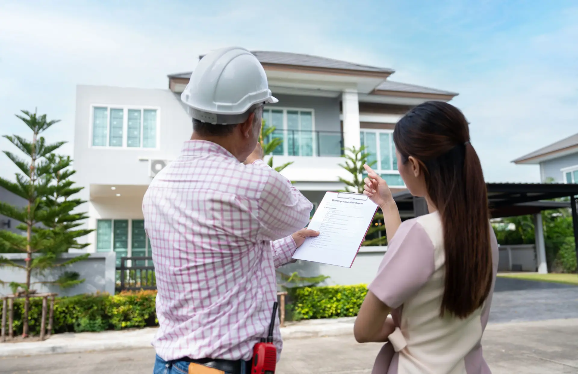 Property owner reviewing a checklist with a contractor outside a home