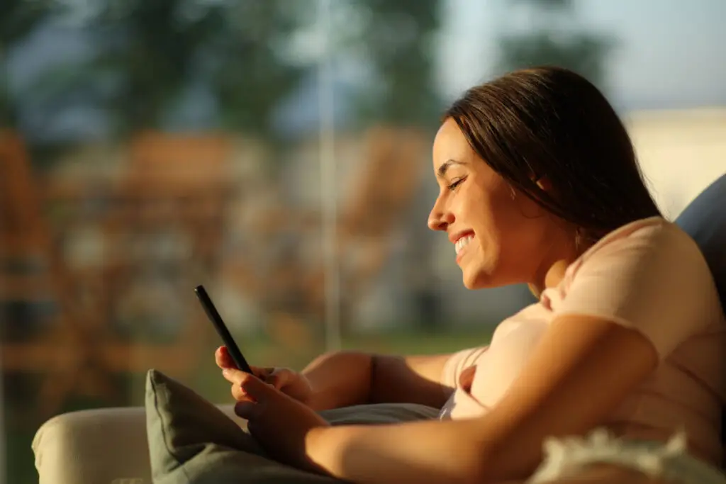 Smiling woman checking her phone at home