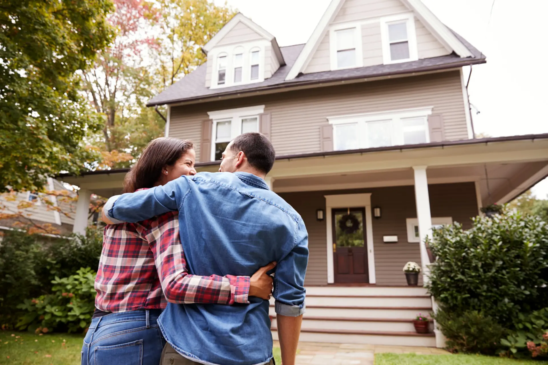 Couple with their arms around each other in front of a two story home